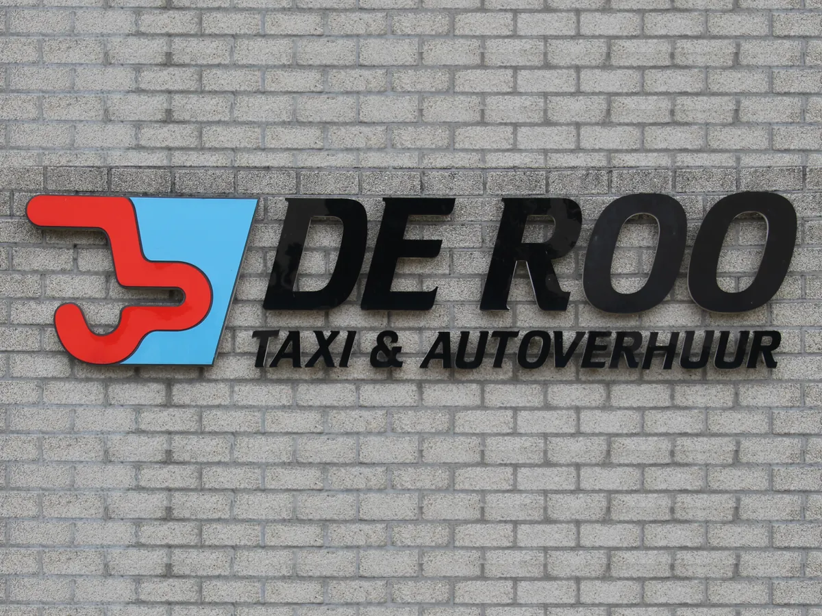 Het De Roo-logo in drie dimensies op een bakstenen gevel